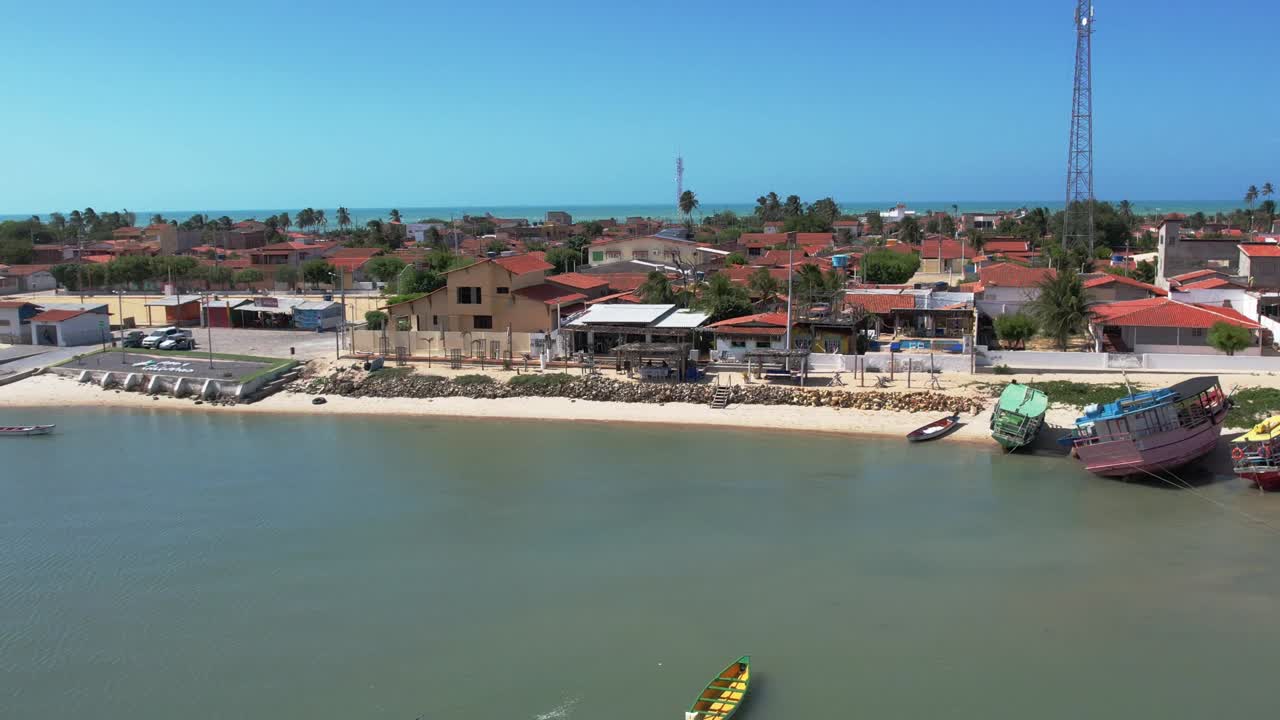 barcos de pesca flotando en el mar con casas frente al mar en verano en galinhos, río grande del norte, brasil