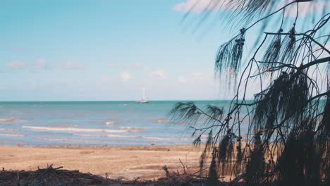 a small boat floats in beautiful, blue, tropicic waters under a warm, sunny sky just off the coast of a rocky beach