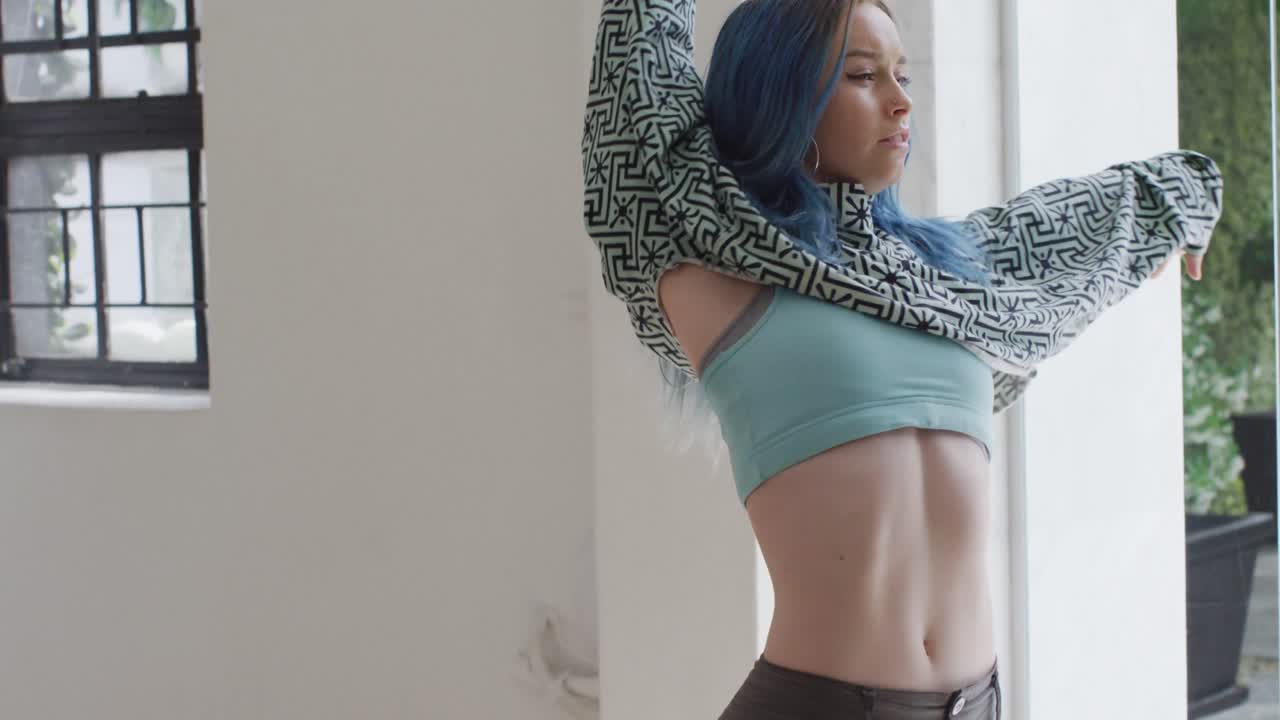 염색 된 머리카락을 가진 백인 여성 댄서가 댄스 스튜디오에서 혼자 춤을 추고, 느린 동작