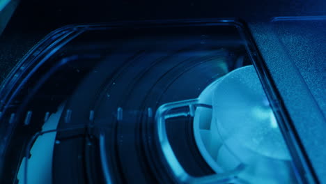 old video recorder inside close-up, vhs. retro player in neon blue light, vintage video cassette broadcasting, audio tape.