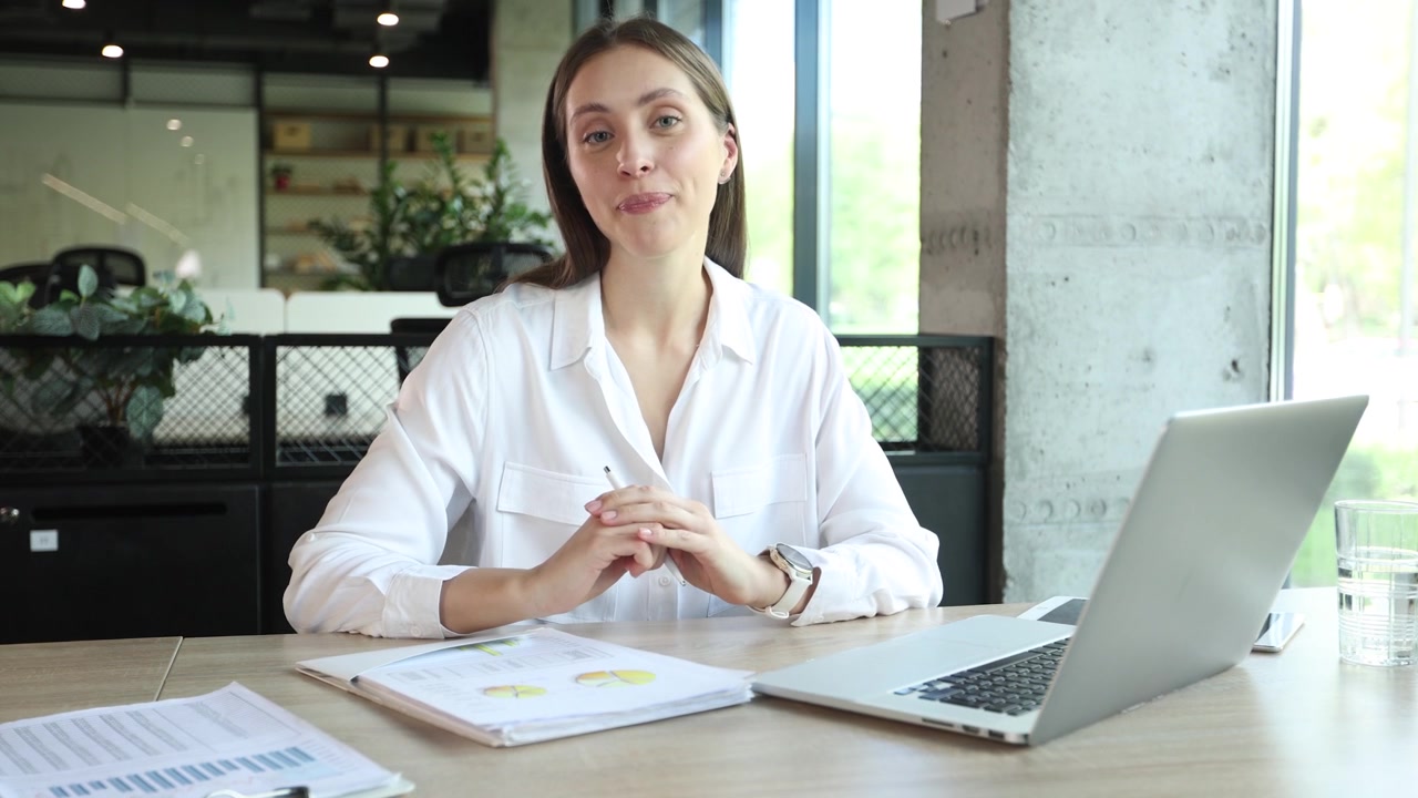 Joven empresaria hablando y trabajando en su portátil en la oficina