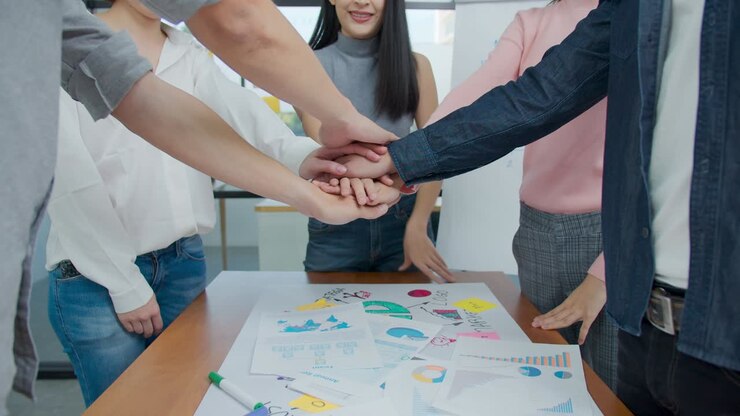 4K UHD : Group of happy young asian employee joining stack hands together, laughing and smiling together in brainstorm meeting at office. Casual business with startup teamwork community celebration.