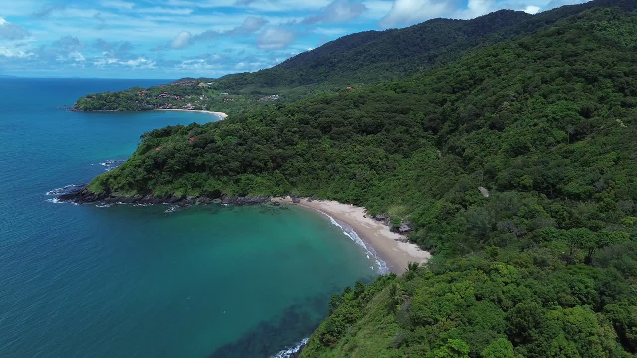 Aerial drone view of secluded tropical beach on Koh Lanta with lush green hills and dense forest, calm turquoise water, untouched coastline and peaceful natural scenery, captured with no people