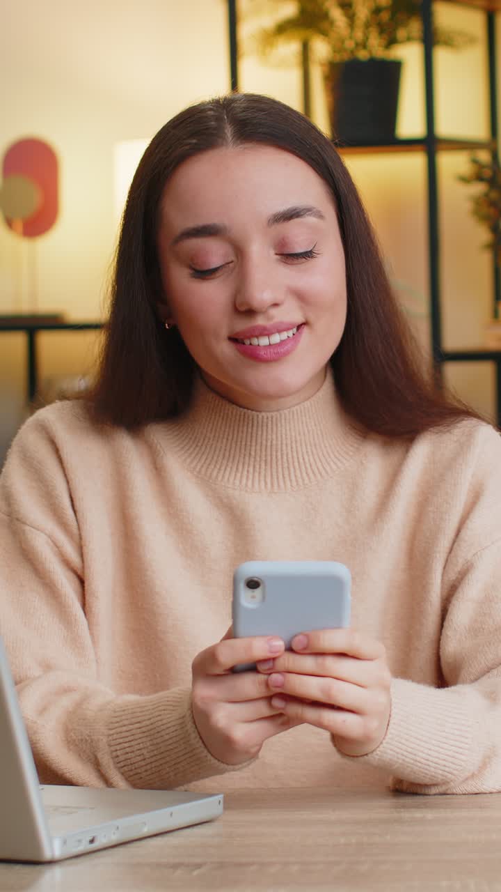 giovane donna caucasica si siede a tavola a casa usa lo smartphone condivide messaggi su applicazioni di social media