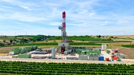 Oil-Drilling-Rig-In-The-Middle-Of-Agricultural-Fields---aerial-shot