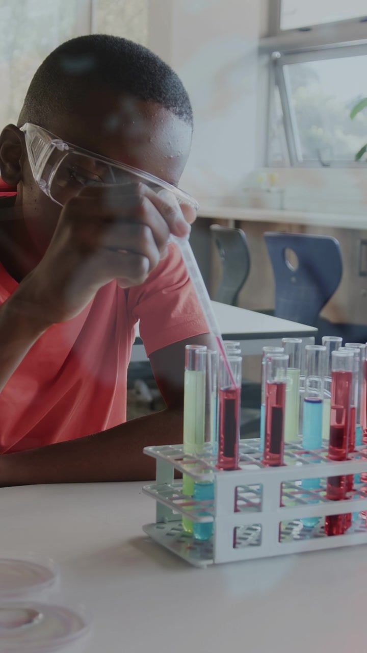 Vertical video: Boy lifting pipette, adding drops while overlays over hands and tubes for science