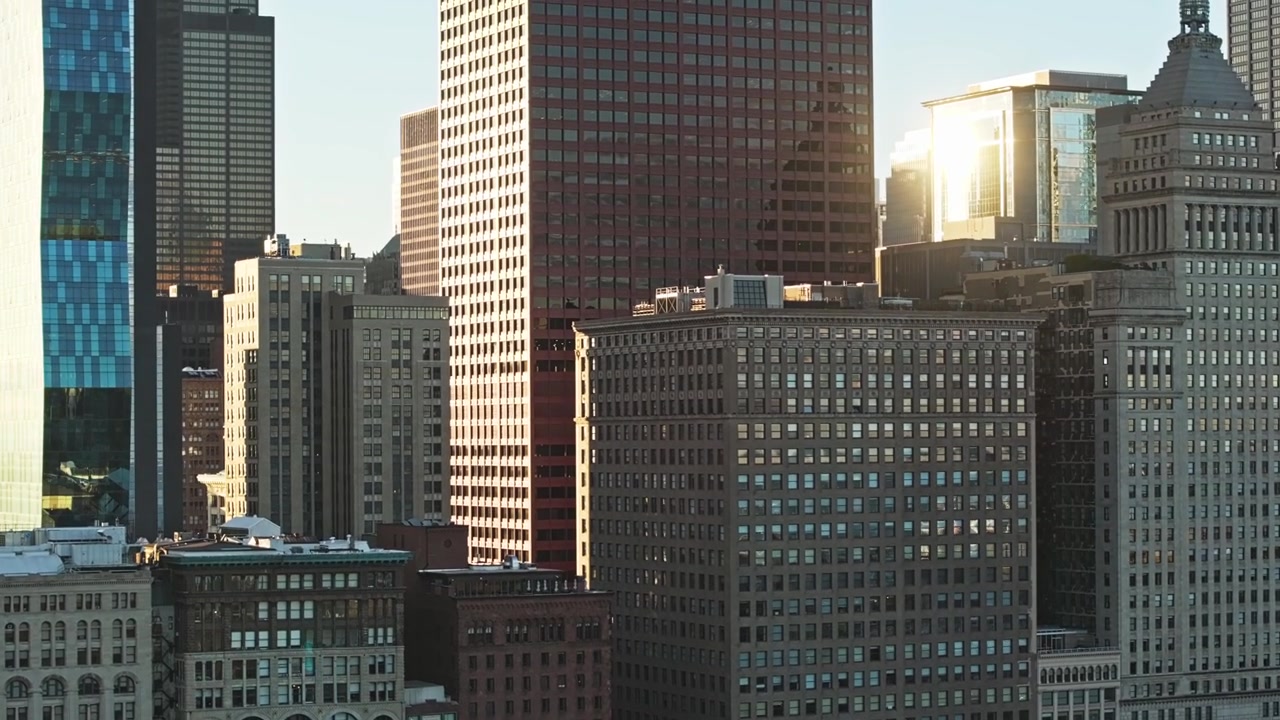 Rastreamento aéreo com teleobjetiva para a direita sobre o horizonte do centro de Chicago ao pôr do sol, com arranha-céus cintilantes, reflexo solar e edifícios de vidro