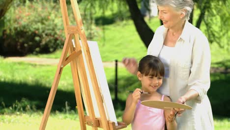Young-girl-painting-a-canvas-with-grandmother
