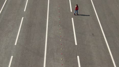 Woman athlete rides on roller skates, makes a figure eight by kicking. Slalom elements, criss cross. Aerial view, professional roller skating training. 4k, 10bit, ProRes