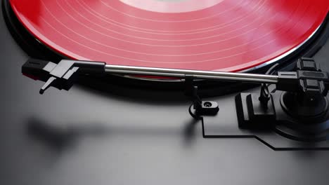 removing red vinyl record from a turntable. process of putting aside red lp from a record player - close up of a tone arm