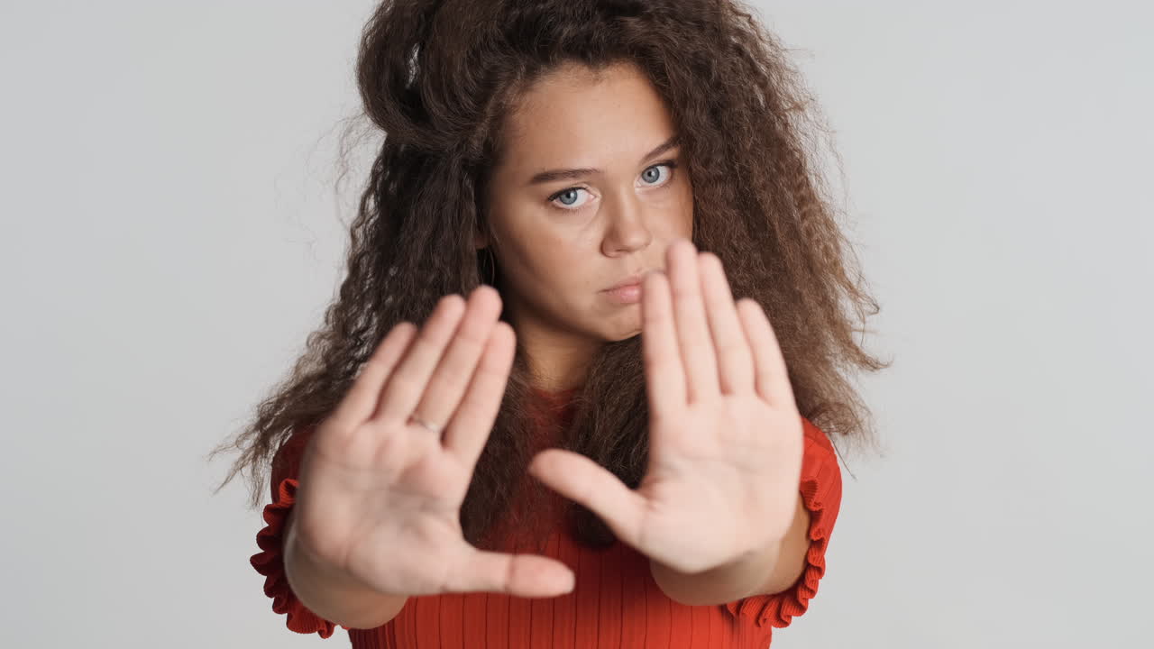 Caucasian curly haired woman showing stop gesture.