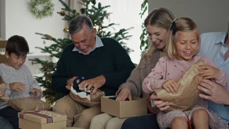 caucasian family opening christmas presents together at home.