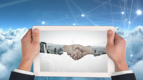 holding tablet, hands shaking over cityscape and cloud network