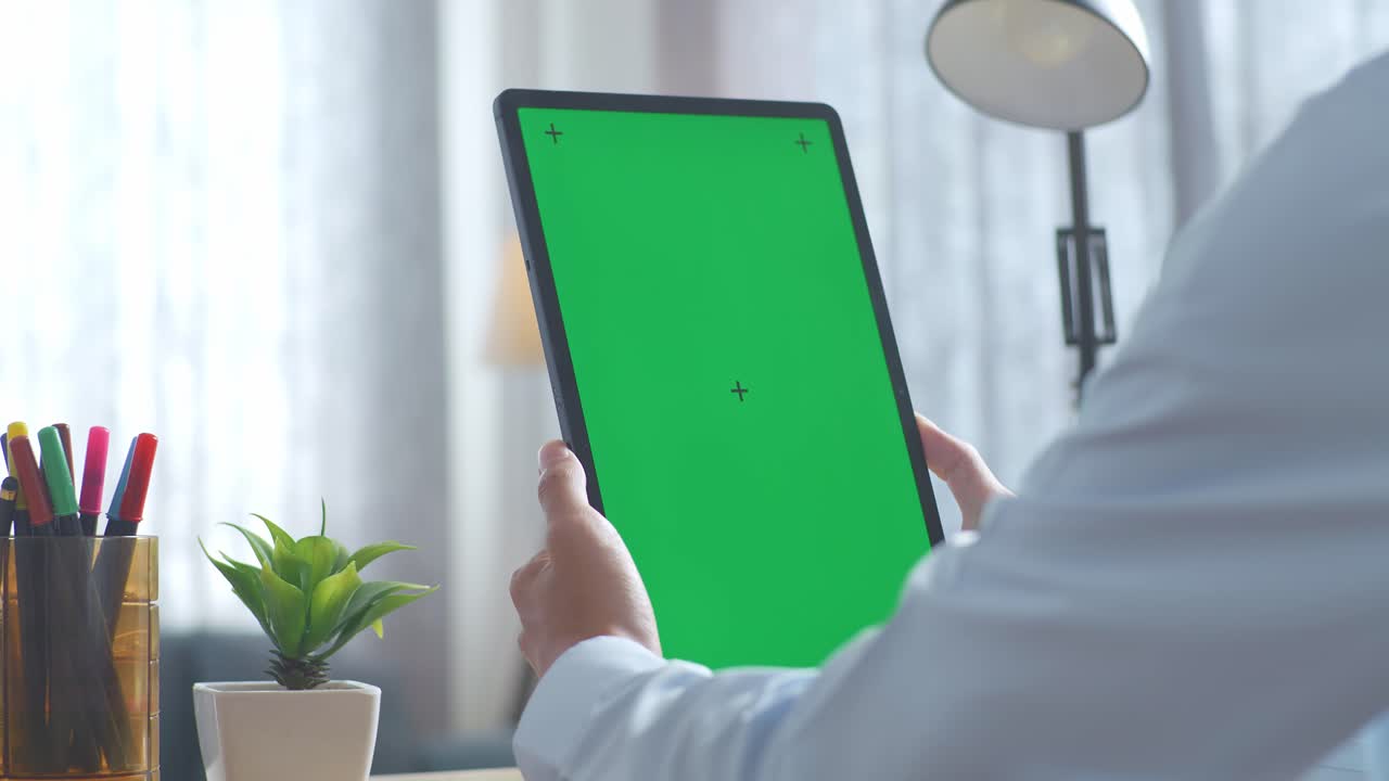 persona que sostiene una tableta con una pantalla verde