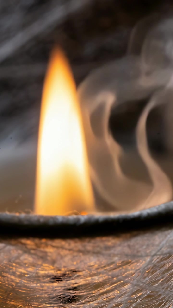 Vertical video: Flickering candle flame, wick glowing after lighting, with dish rim for warm light