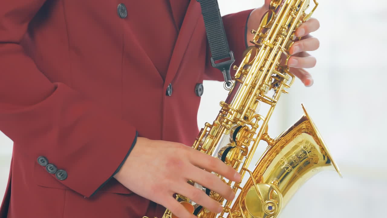 Professional musician's hand playing a saxophone with golden instrument details, player's fingers pressing keys rapidly moving over the instrument's buttons, this brass instrument