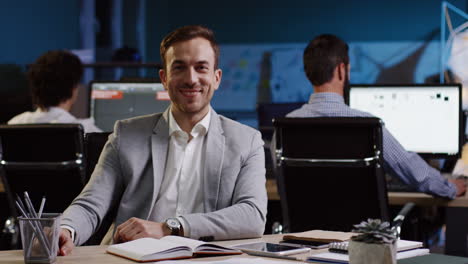 close-up view of young caucasian businessman smiling at camera sitting at desk in the office