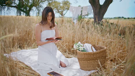 picnic model riffling novel pages in summer field. woman reading book at nature