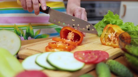 Female-hands-of-housewife-with-a-knife-cut-fresh-bell-pepper-on-chopping-Board-kitchen-table