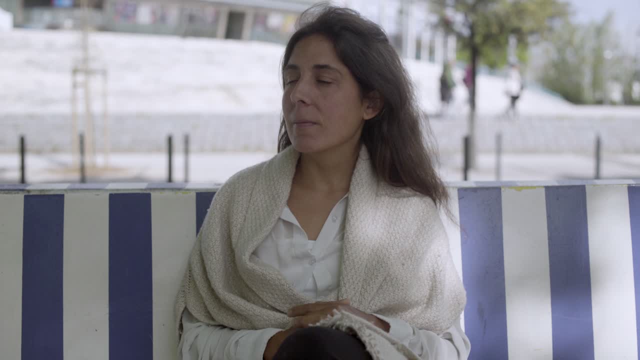 Bella donna di mezza età seduta su una panchina che si guarda intorno
