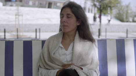 Beautiful-middle-aged-woman-sitting-on-bench-and-looking-around.