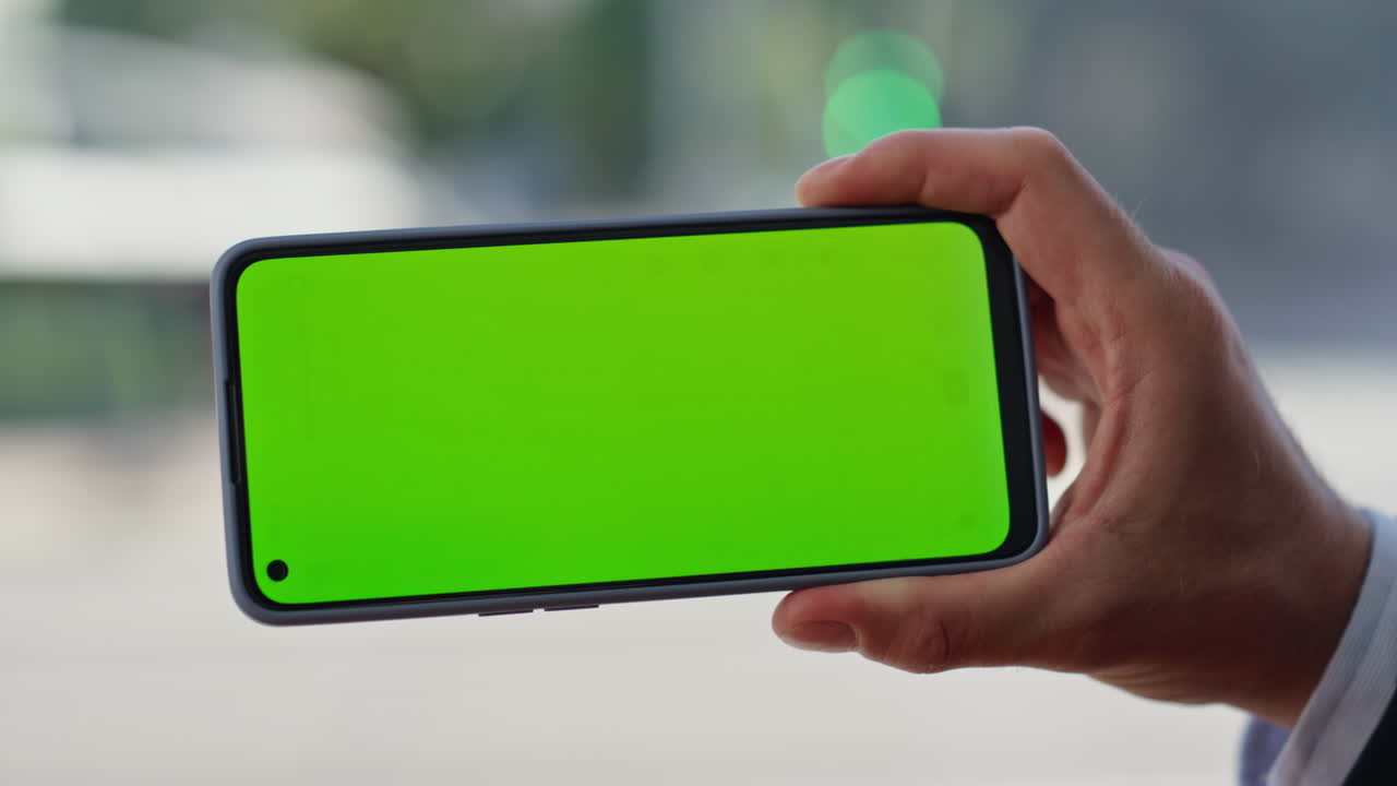 Hand touching green screen smartphone holding at panoramic window alone closeup