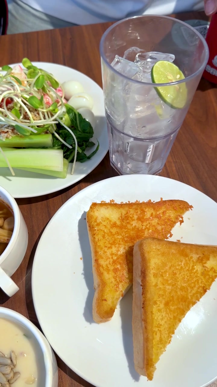 Una panorámica de cámara cenital revela una comida de bistec de cerdo a la parrilla con ensalada, tostadas y sopa.