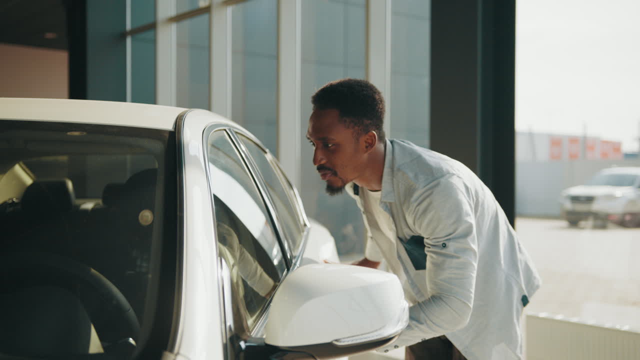 человек смотрит на белую машину в шоу-руме