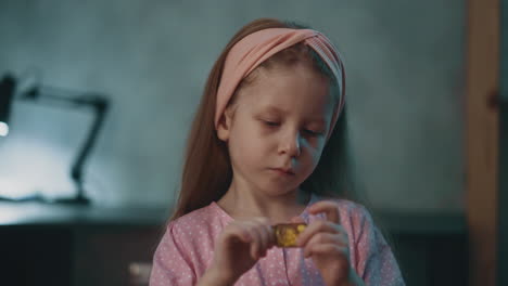 Interested-child-plays-with-closed-bottle-of-pills-in-room