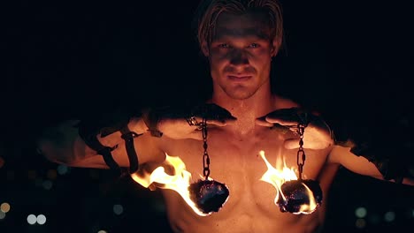 Young-blond-male-holds-two-pois-hanging-on-chains-raises-them-then-lowers-them-Face-and-neck-are-sweaty