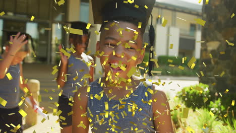 animation of gold confetti over happy biracial schoolboy wearing mortarboard outside school