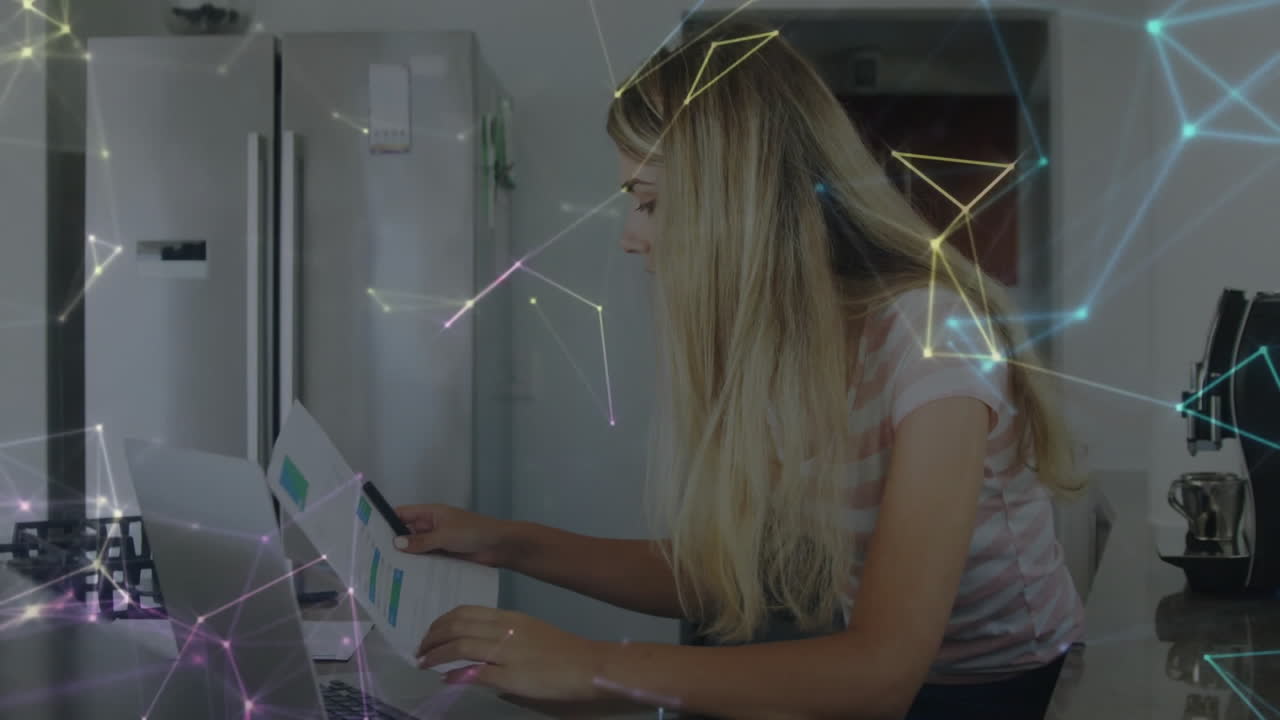 Woman reviewing finance charts while working on kitchen countertop, overlay showing network nodes