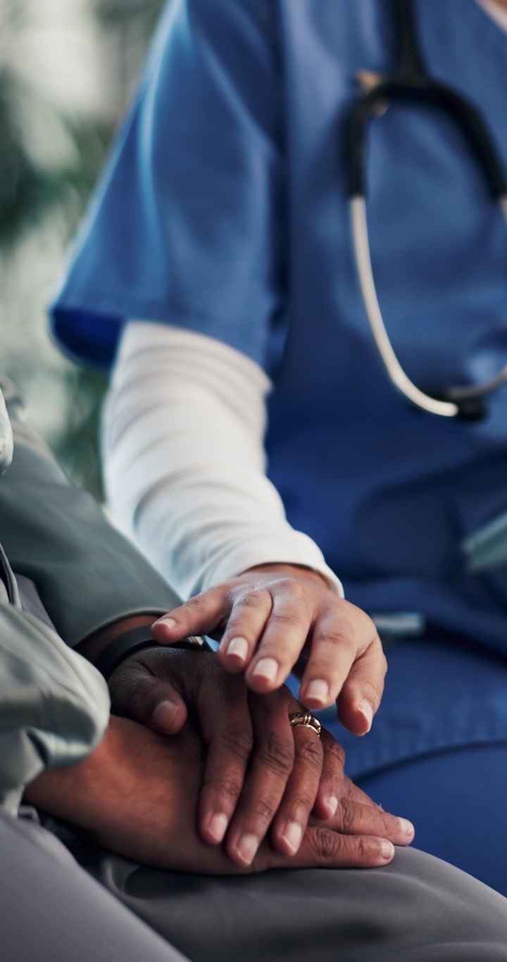 Medico che conforta un paziente tenendogli le mani nello studio medico.