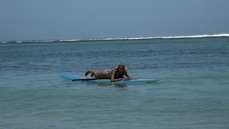 pretty young girl lying alone on paddle board on indian ocean in summer