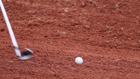 golf club hitting ball in sand bunker.