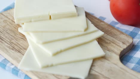 sliced cheese on a wooden cutting board with tomatoes