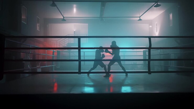 Sagome di due pugili che si allenano in un ring di pugilato buio