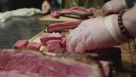 chef cuts freshly grilled venison meat on wooden cut board at meat tasting event