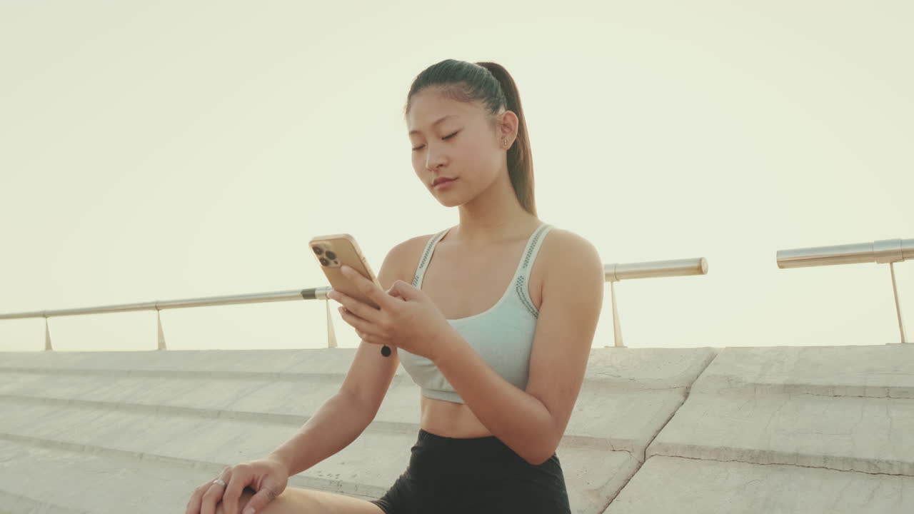 Young woman using phone after exercise