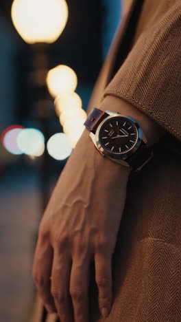person wearing a watch and coat in an urban night setting