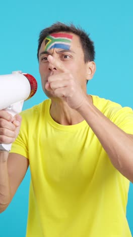 excited man with south african flag on face using a megaphone