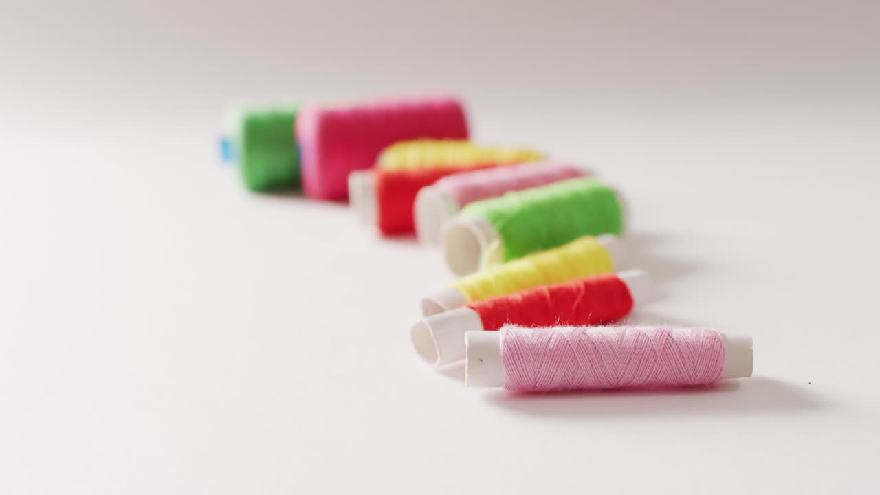 vídeo de bobinas de hilos de bordado de colores en una fila sobre fondo blanco con espacio para copiar