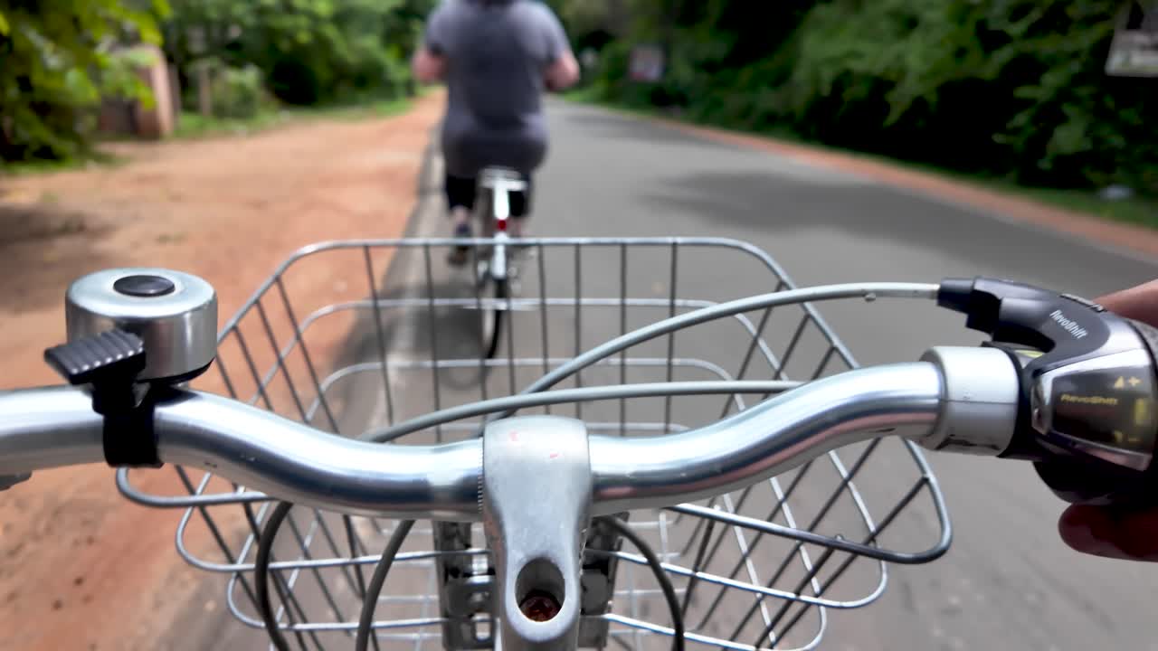 Experience the joy of cycling from a first-person perspective. View from the handlebar with a basket, capturing cyclists on a group tour through a scenic route.
