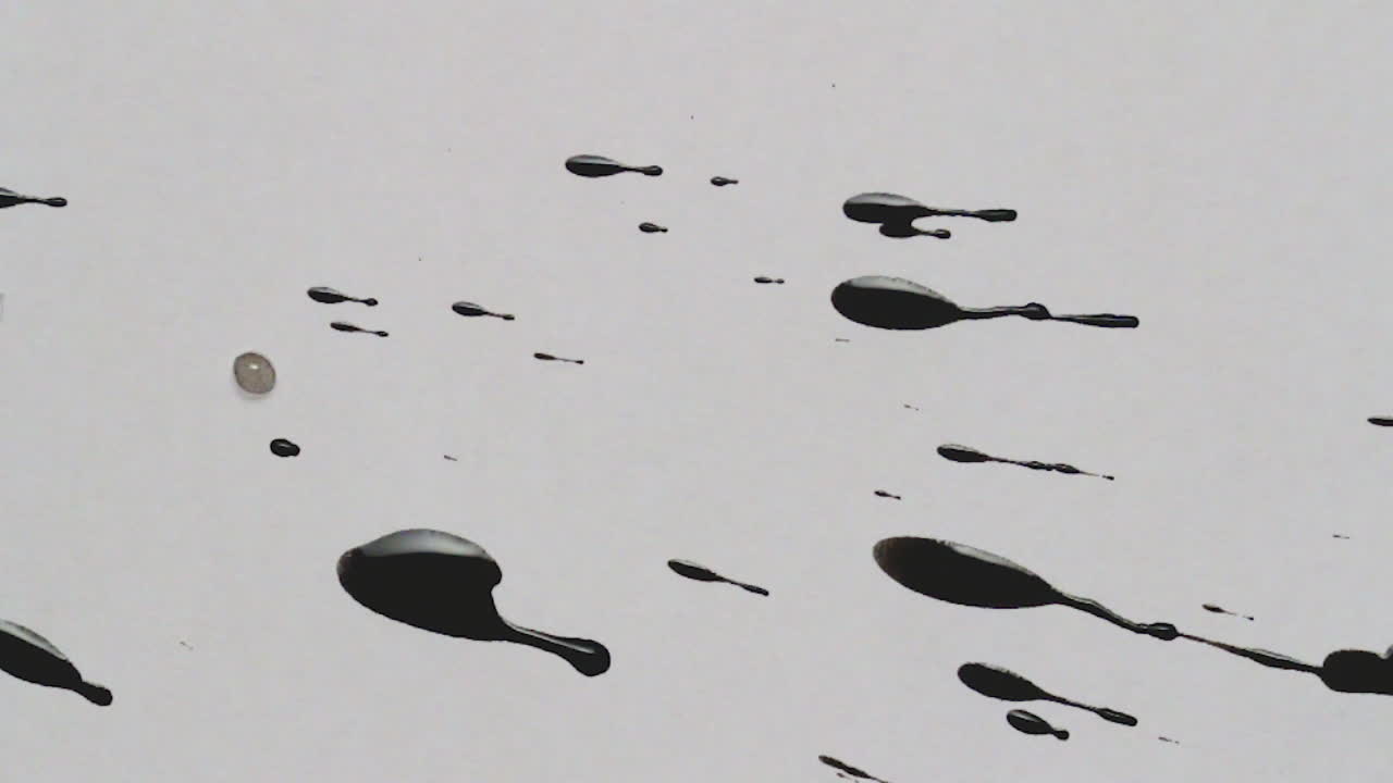 Bidikan atas, bidikan makro, dan close-up berbagai noda tinta hitam yang menetes di atas kertas kreatif putih bertekstur