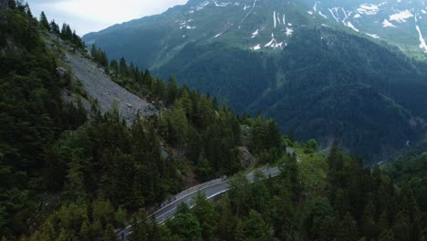 flying along the idyllic mountain cliff serpentine road plöckenpass in the natural austrian and italian alps in summer with green forest trees and blue peaks