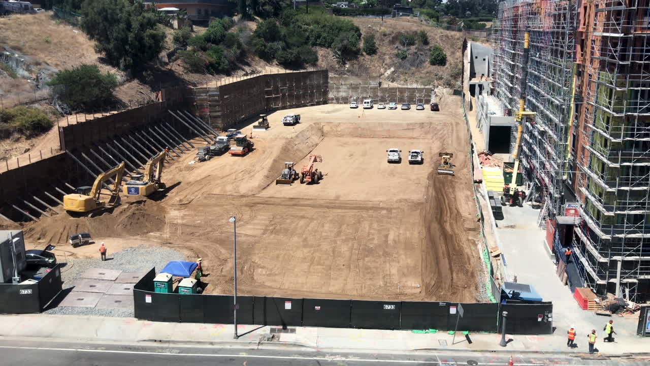 los trabajadores se mueven alrededor del sitio de construcción construyendo un nuevo rascacielos en una ciudad