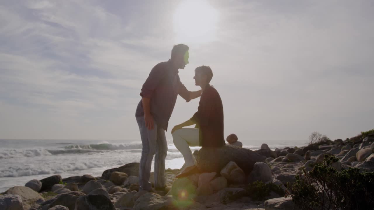 pareja caucásica disfrutando del tiempo libre en el mar en un día soleado, hombre besándose