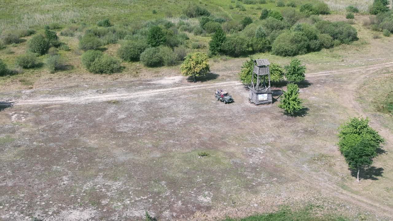 A group of travellers arriving at a wooden watchtower