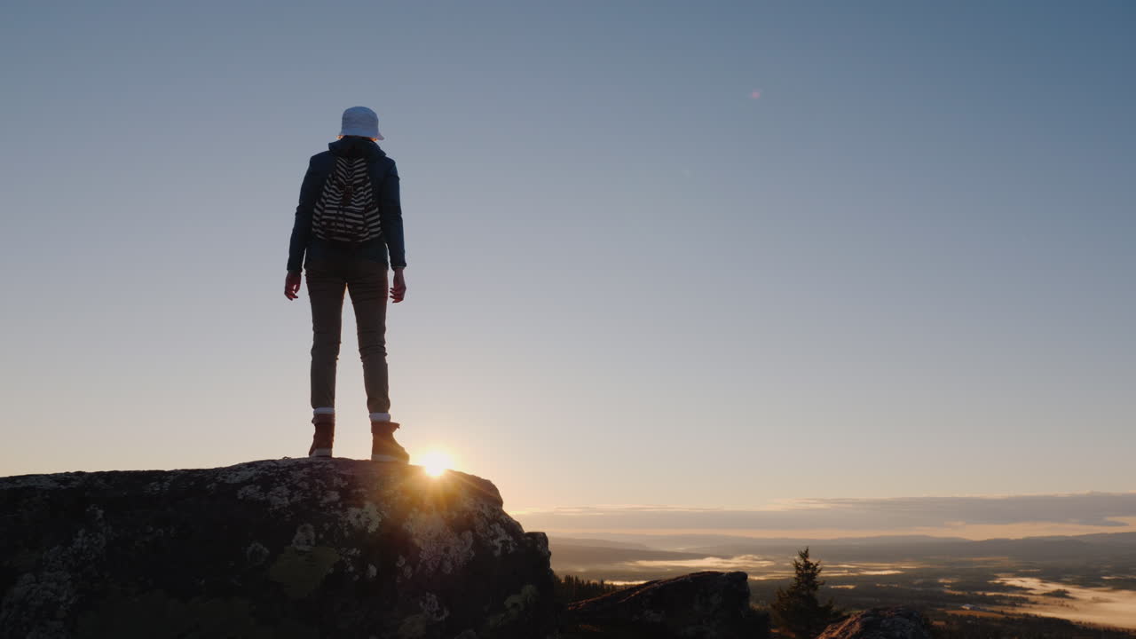 mujer viajera agitando una gorra en la cima de la montaña éxito y vacaciones activas en noruega