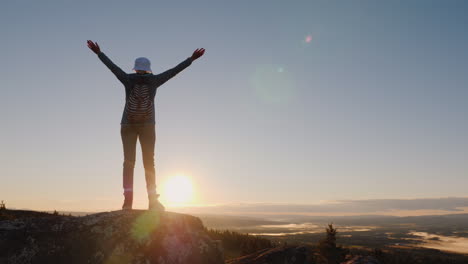 mujer viajera agitando una gorra en la cima de la montaña éxito y vacaciones activas en noruega